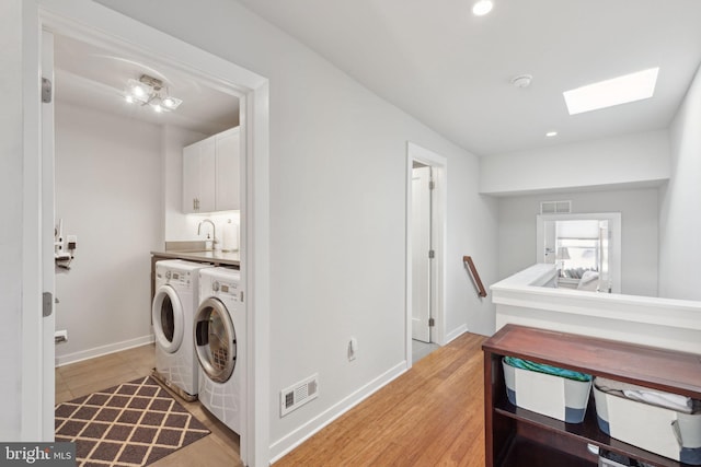 laundry area with cabinets, washer and dryer, and light wood-type flooring