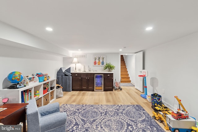 rec room with beverage cooler, light wood-type flooring, and indoor wet bar