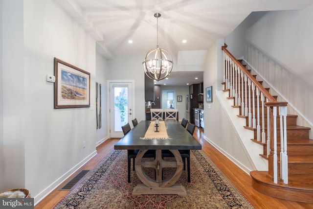 dining space with hardwood / wood-style flooring and an inviting chandelier