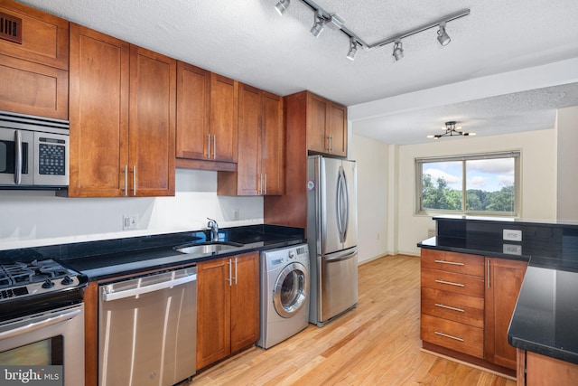 kitchen featuring appliances with stainless steel finishes, a textured ceiling, washer / clothes dryer, and sink