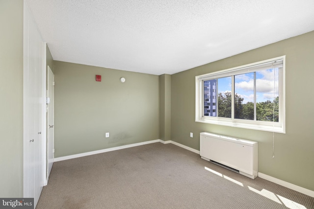 carpeted empty room featuring a textured ceiling and radiator