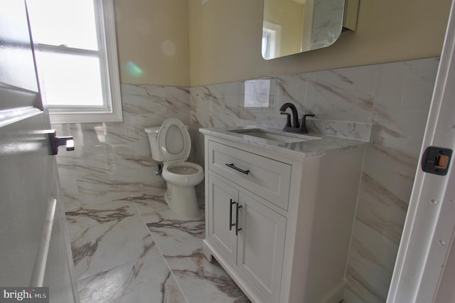 bathroom with vanity, tile walls, and toilet