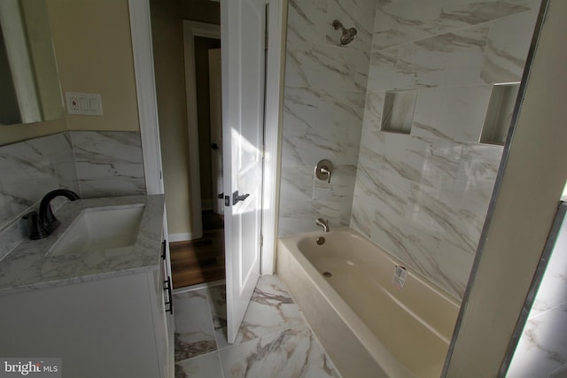 bathroom featuring vanity, tiled shower / bath combo, and tile walls