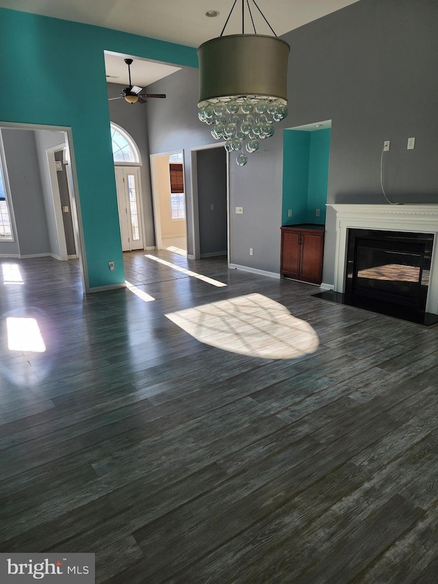 unfurnished living room featuring a fireplace with flush hearth, a wealth of natural light, baseboards, and dark wood-style floors