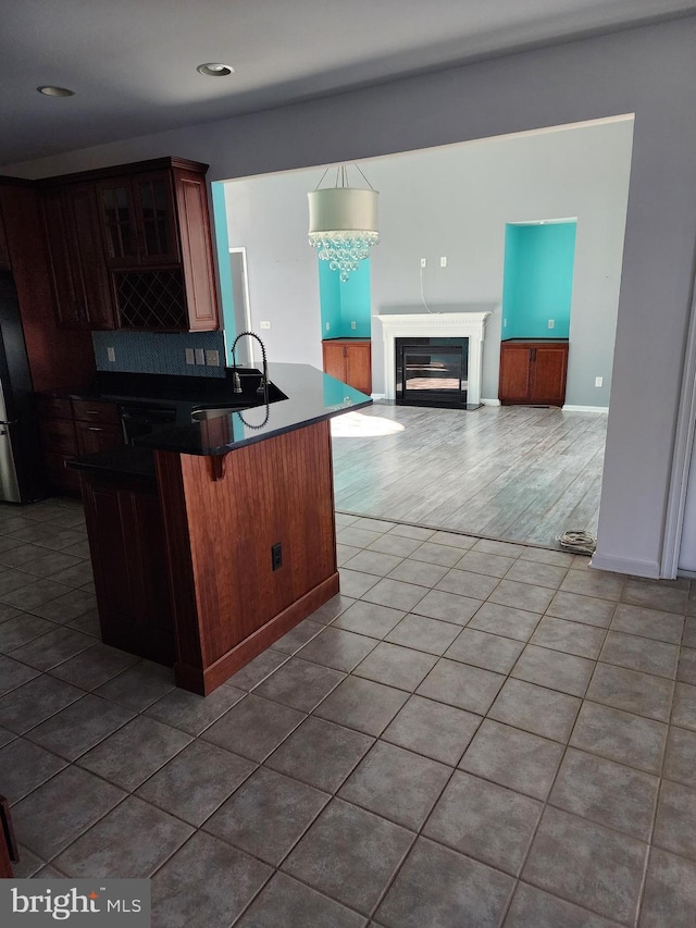 kitchen featuring a breakfast bar area, dark countertops, open floor plan, a sink, and tile patterned floors