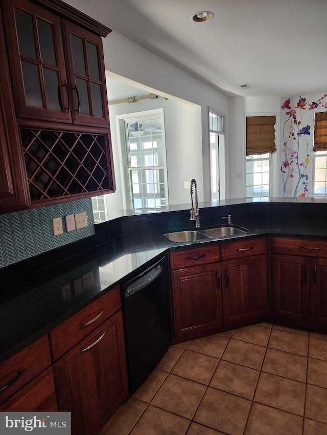 kitchen featuring glass insert cabinets, dark countertops, black dishwasher, and a sink