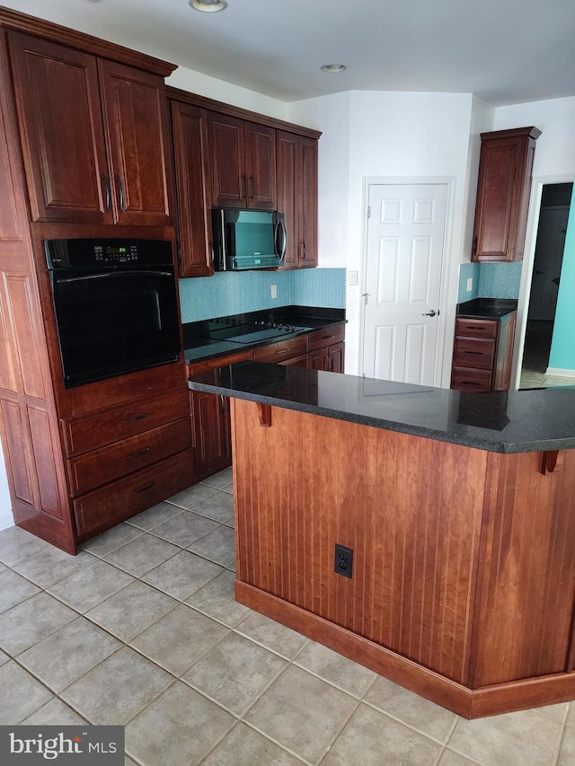 kitchen with a kitchen bar, dark countertops, decorative backsplash, and black appliances