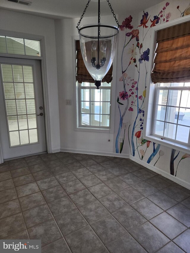 unfurnished dining area featuring dark tile patterned floors, visible vents, and baseboards