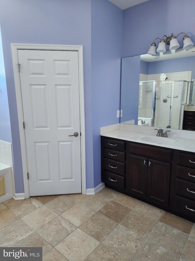 full bathroom with vanity, baseboards, a shower stall, stone finish floor, and a bathtub