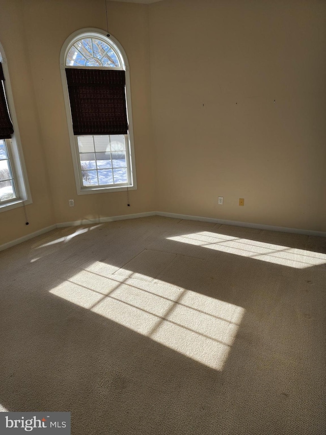 unfurnished room with a wealth of natural light, baseboards, and carpet flooring