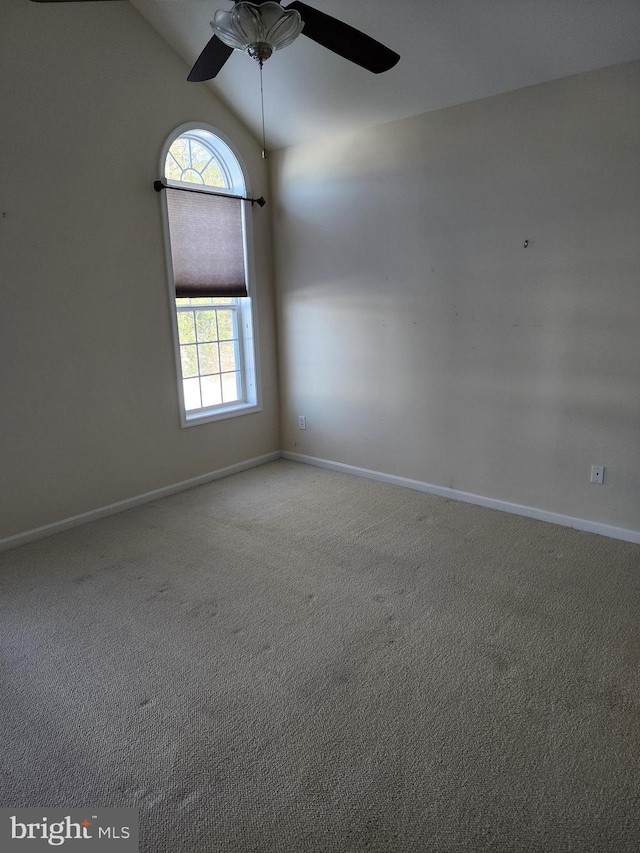 unfurnished room with carpet floors, vaulted ceiling, baseboards, and a ceiling fan