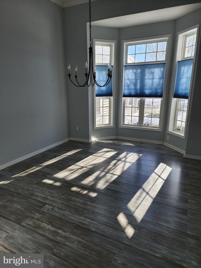 unfurnished dining area featuring a notable chandelier, baseboards, and dark wood-type flooring