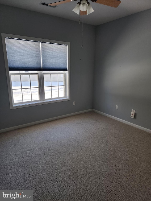 carpeted empty room featuring visible vents, ceiling fan, and baseboards