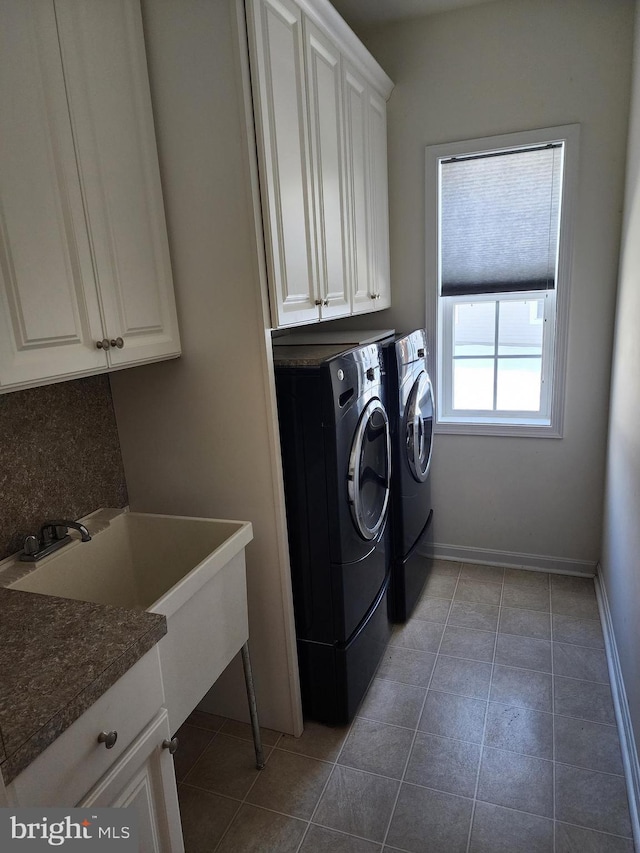 clothes washing area with washer and dryer, cabinet space, baseboards, and light tile patterned flooring