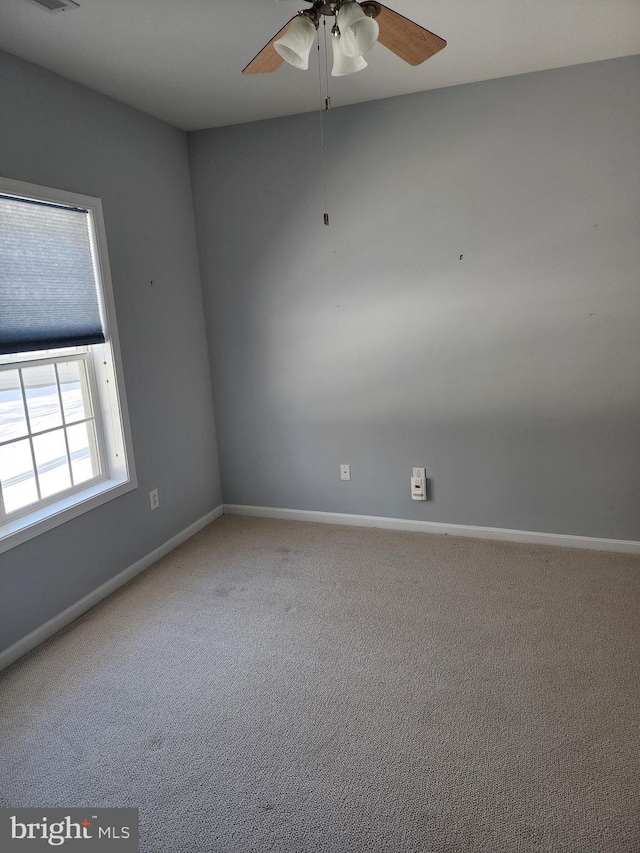 carpeted empty room with ceiling fan and baseboards