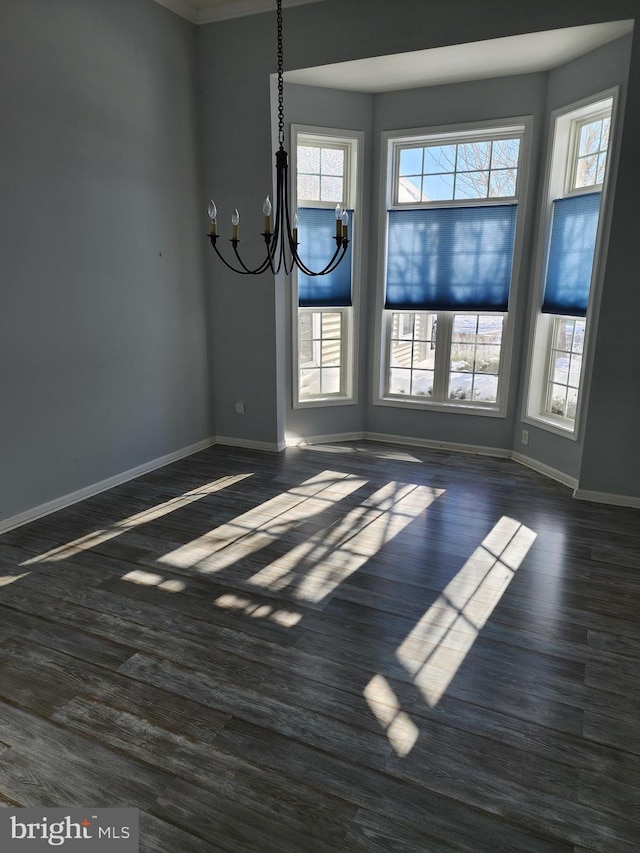 unfurnished dining area with a chandelier, dark wood finished floors, and baseboards