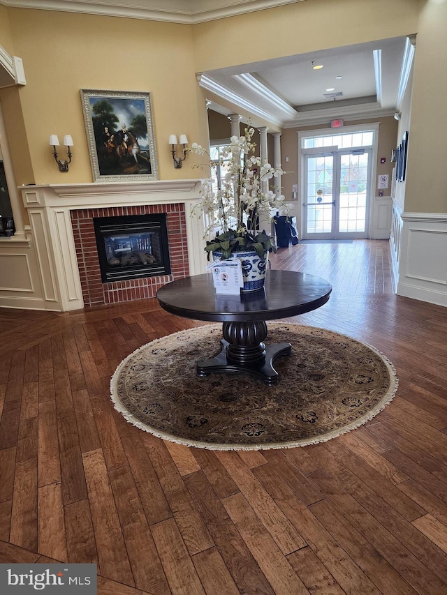 dining room featuring crown molding, dark wood-type flooring, a fireplace, and a decorative wall