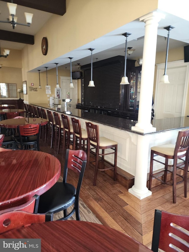 dining area featuring beam ceiling, decorative columns, and wood finished floors