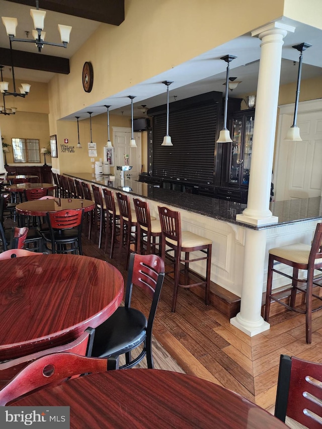 dining area featuring decorative columns, wood finished floors, and beamed ceiling