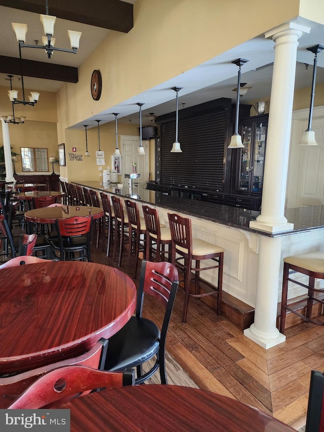 dining room featuring beam ceiling, wood finished floors, decorative columns, and an inviting chandelier