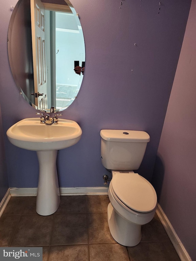 bathroom with toilet, baseboards, and tile patterned floors