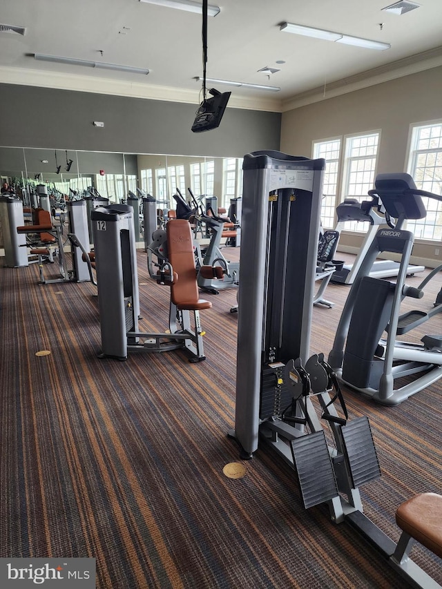 gym with dark carpet, visible vents, and crown molding