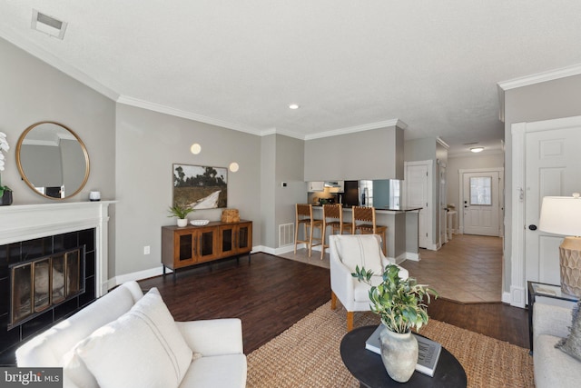 living room featuring hardwood / wood-style flooring, ornamental molding, and a tile fireplace