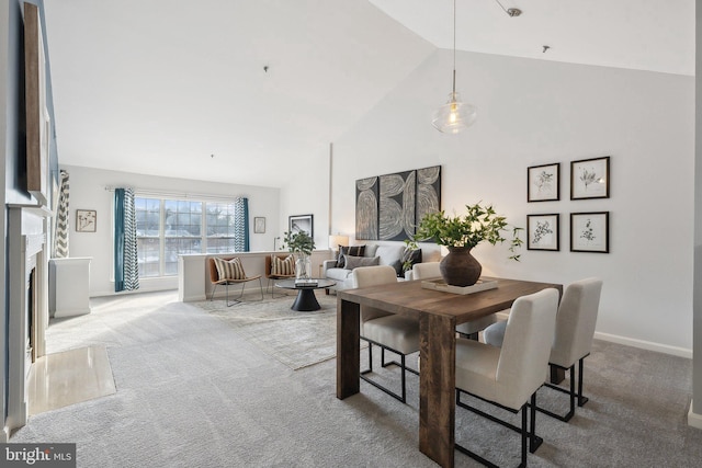 carpeted dining area with high vaulted ceiling