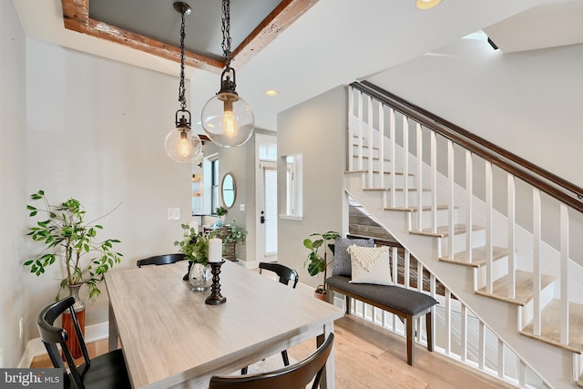 dining space featuring beamed ceiling and light wood-type flooring