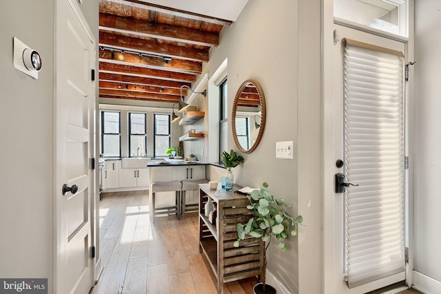 interior space featuring beamed ceiling, light hardwood / wood-style flooring, and sink