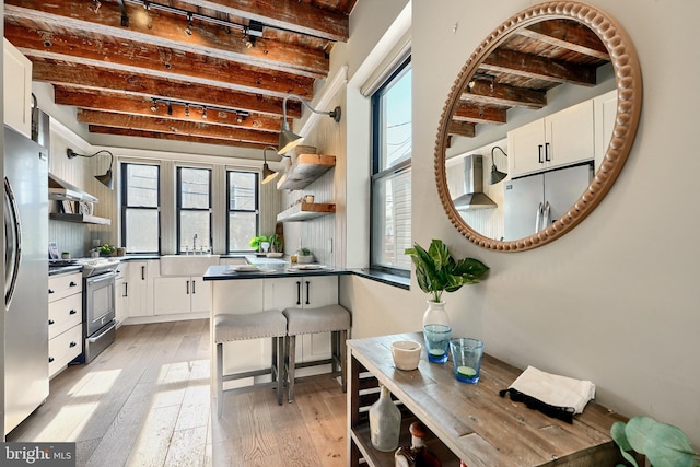 kitchen with beamed ceiling, appliances with stainless steel finishes, and white cabinetry