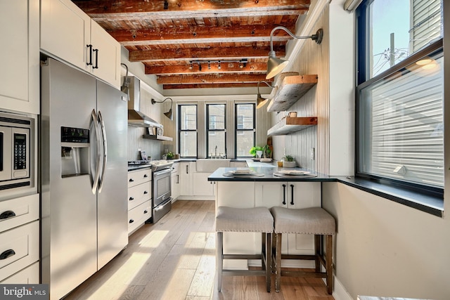 kitchen with light hardwood / wood-style flooring, beamed ceiling, brick ceiling, white cabinets, and appliances with stainless steel finishes