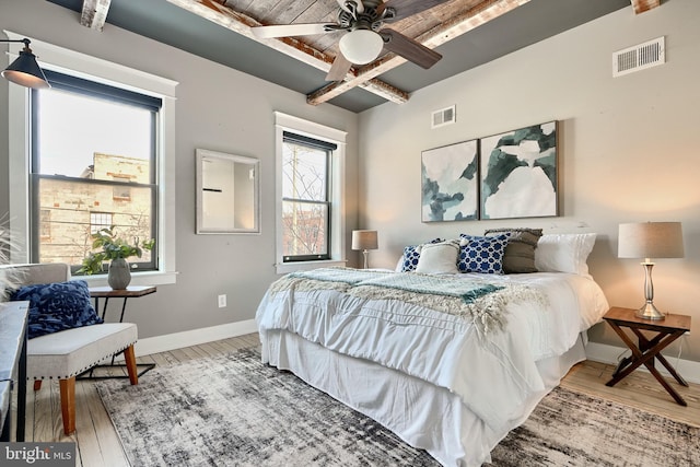 bedroom with beam ceiling, ceiling fan, hardwood / wood-style floors, and wooden ceiling