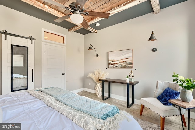 bedroom featuring wooden ceiling, ceiling fan, a barn door, light wood-type flooring, and beamed ceiling