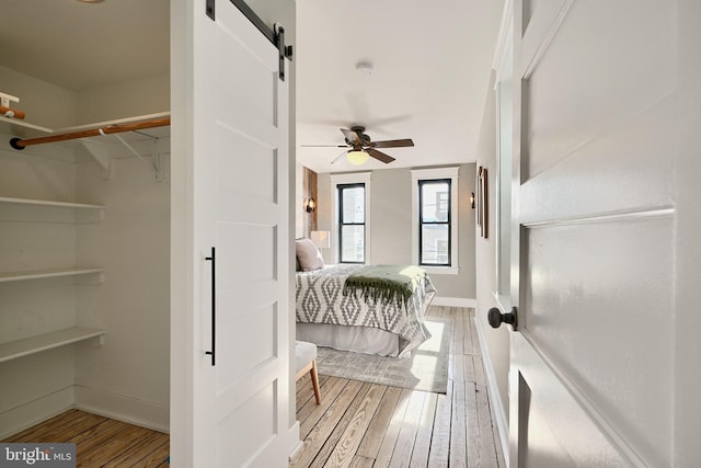 bedroom featuring a barn door, ceiling fan, and hardwood / wood-style floors