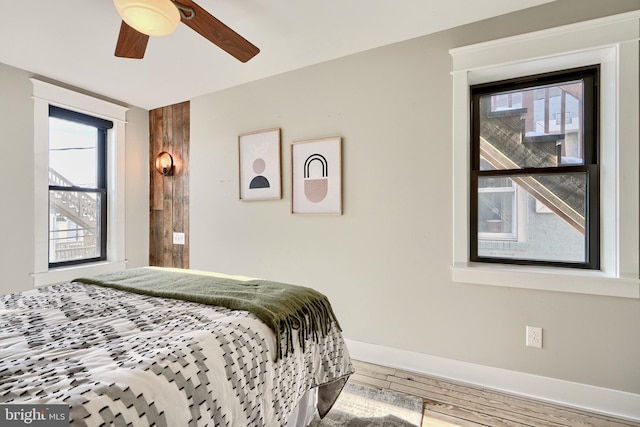 bedroom with multiple windows, wood-type flooring, and ceiling fan