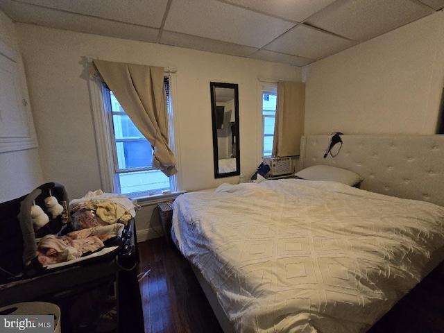 bedroom with a drop ceiling and dark wood-type flooring