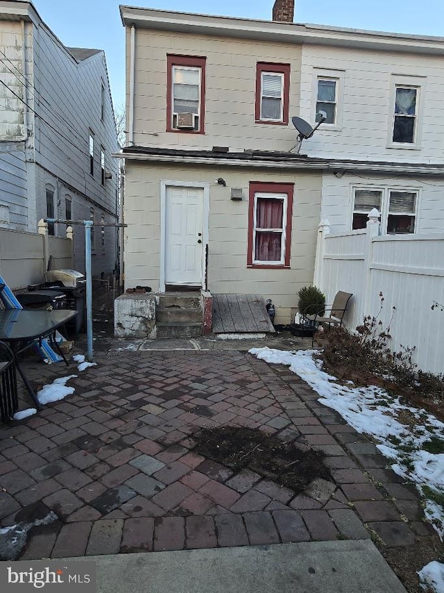 snow covered back of property with a patio