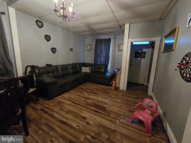 living room featuring a paneled ceiling, dark hardwood / wood-style flooring, and an inviting chandelier