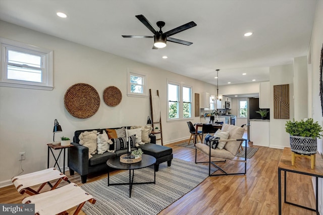 living room with light hardwood / wood-style flooring and ceiling fan with notable chandelier