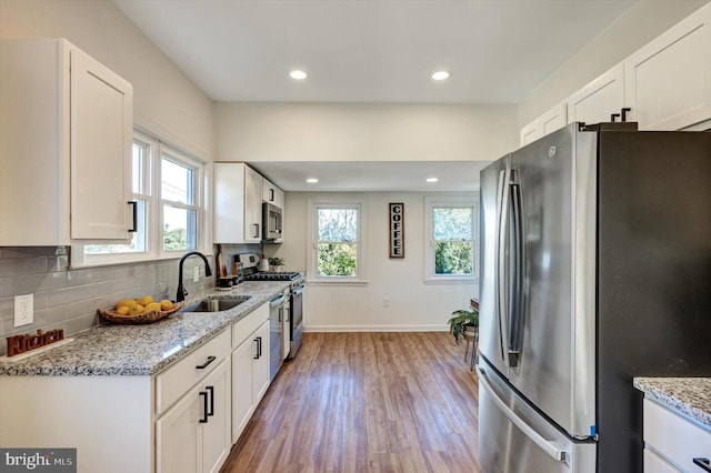 kitchen with sink, white cabinetry, light stone countertops, and appliances with stainless steel finishes