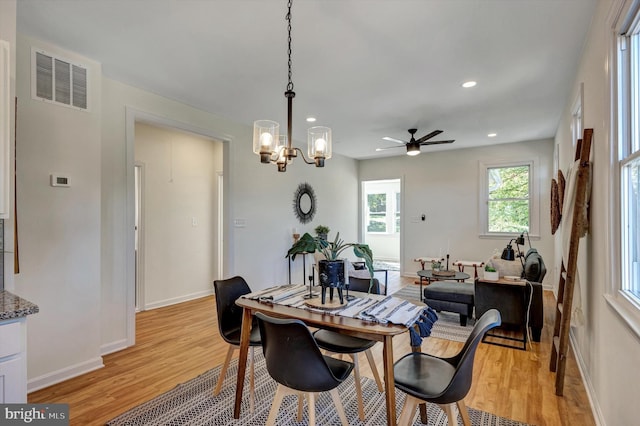 dining room with light hardwood / wood-style floors and ceiling fan with notable chandelier