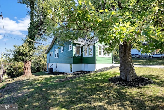 view of side of home featuring cooling unit and a lawn