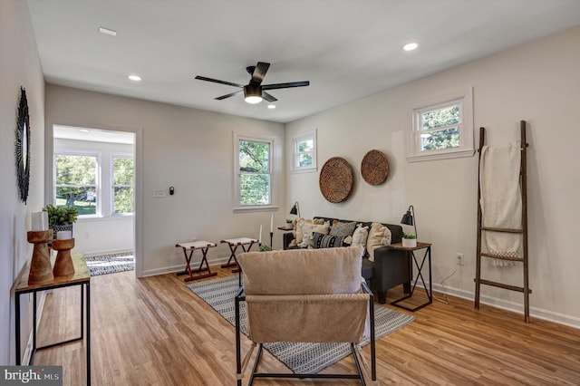 living area with light hardwood / wood-style floors, ceiling fan, and plenty of natural light