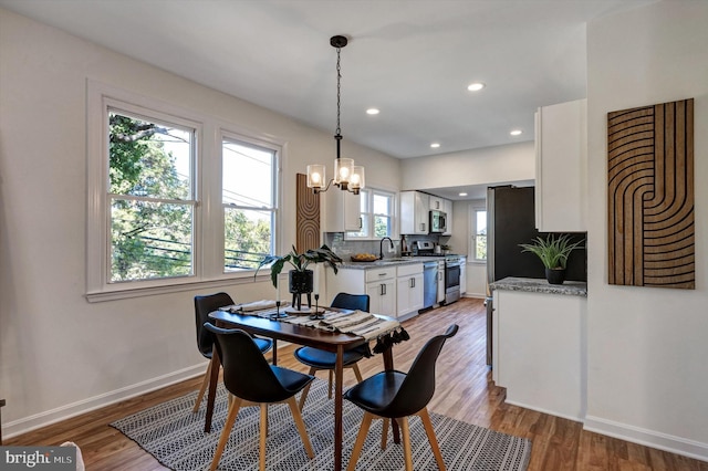 dining space featuring sink, light hardwood / wood-style flooring, and a chandelier