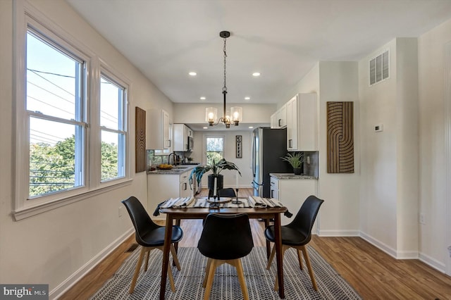 dining room featuring sink, an inviting chandelier, and hardwood / wood-style flooring