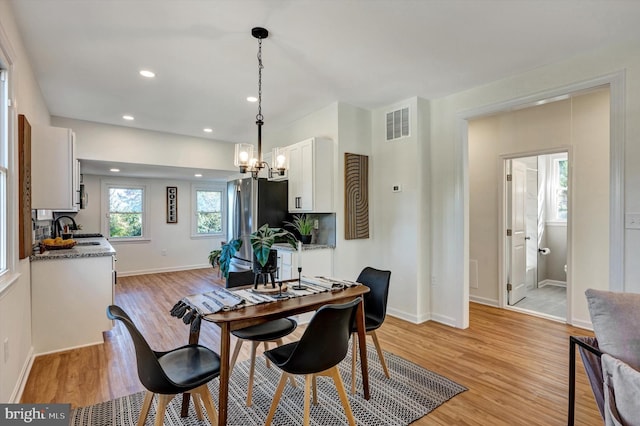 dining area with sink, light wood-type flooring, and a chandelier