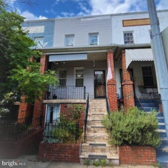 view of property featuring covered porch and brick siding