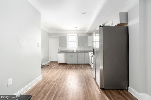 kitchen with gray cabinets, appliances with stainless steel finishes, tasteful backsplash, ornamental molding, and sink