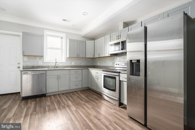 kitchen featuring tasteful backsplash, appliances with stainless steel finishes, sink, and hardwood / wood-style flooring